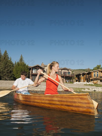 portrait of two young people paddling canoe.