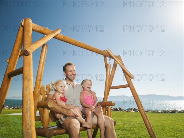 Father with daughters (2-3, 4-5) on swing.