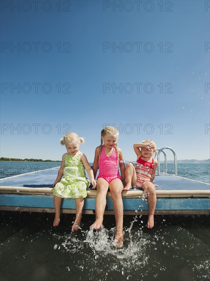 Girls (2-3, 4-5) sitting at the edge of raft and splashing water. Photo: Erik Isakson
