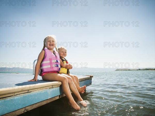 Girls (2-3, 4-5) sitting at the edge of raft in life jackets.