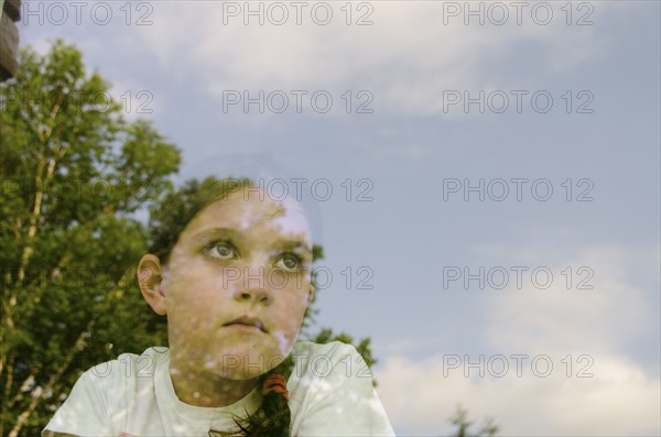 Girl (8-9) looking through window. Photo: Tetra Images