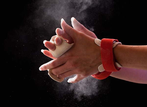 Close-up of gymnast's hands with chalk floating in air around them. Photo: Mike Kemp