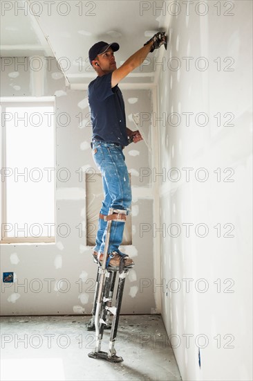 Drywall worker on stilts working on drywall joints. Photo: Mike Kemp