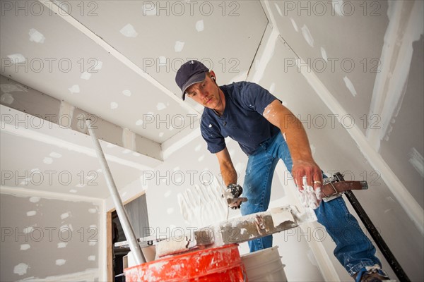 Drywall worker adding drywall mud to his banjo. Photo : Mike Kemp