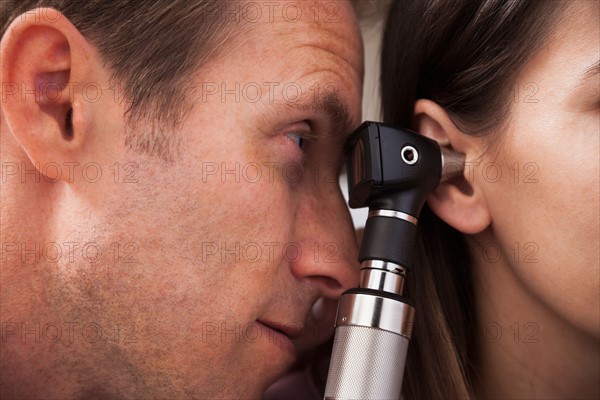 Close-up of doctor doing ear exam with Otoscope. Photo : Mike Kemp