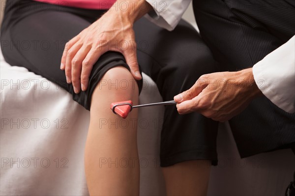 Close-up of doctor checking knee reflexes. Photo : Mike Kemp