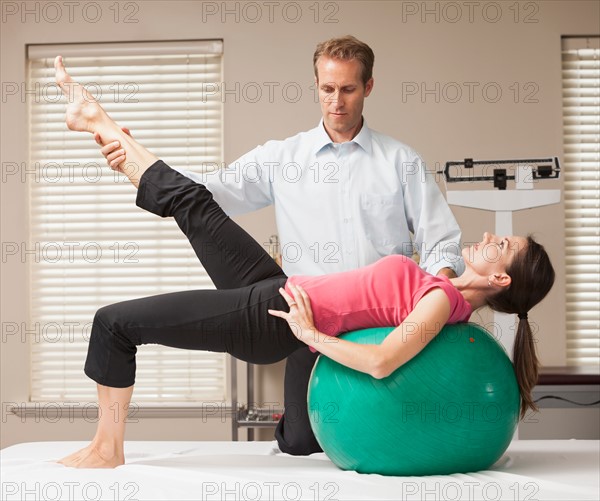 Young woman exercising with help from physical therapist. Photo: Mike Kemp