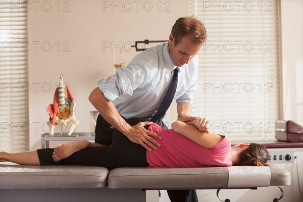 Woman lying on side getting adjusted by chiropractor. Photo : Mike Kemp