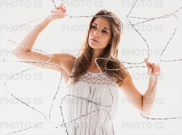 Studio shot of woman behind barbed wire. Photo: Mike Kemp