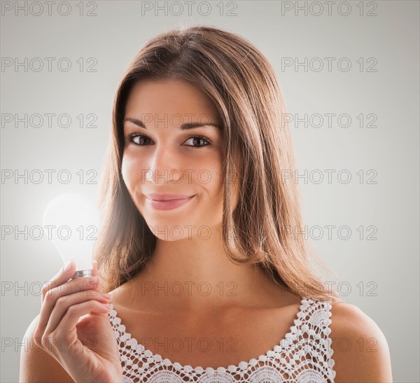 Beautiful woman holding light bulb. Photo : Mike Kemp