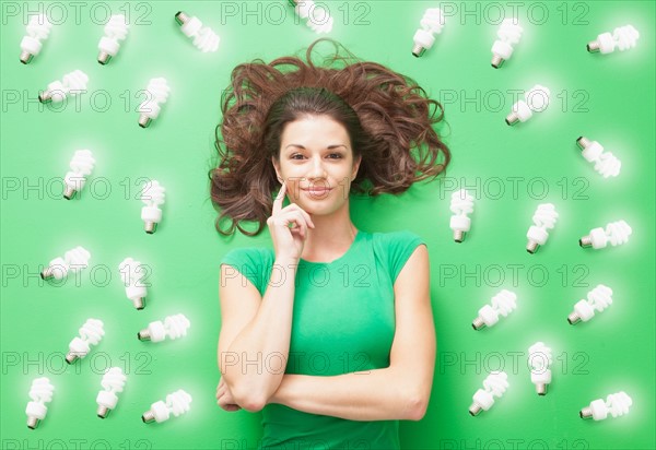 Girl laying on Green background with CF light bulbs around her. Photo : Mike Kemp