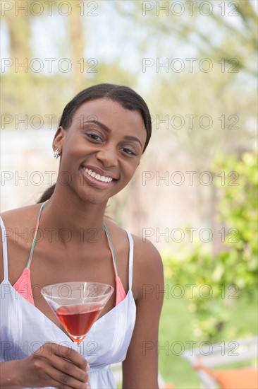 African American woman with drink at garden party. Photo : Dan Bannister