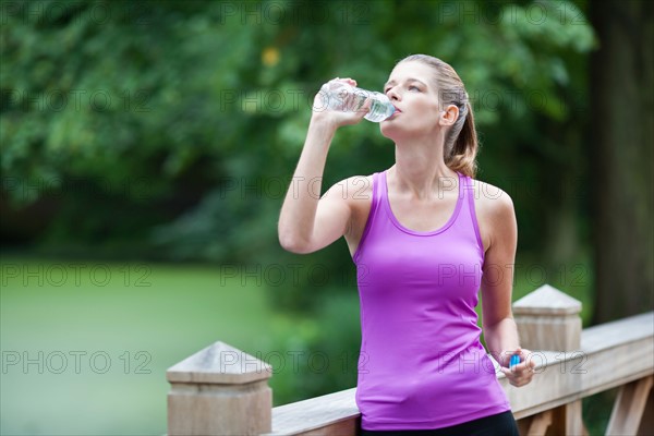 Young woman drinking water from a bottle after running