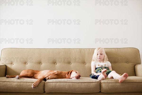 Girl (4-5 years) on couch with dog. Photo : Jessica Peterson