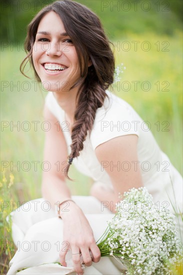 Portrait of young smiling woman holding flowers. Photo : Jessica Peterson