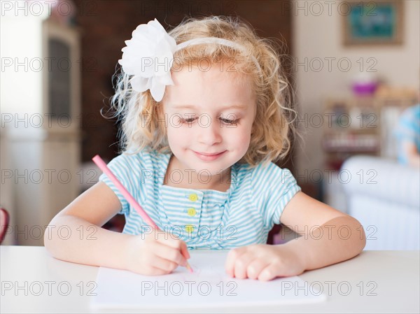 Girl drawing at table and smiling. Photo: Jessica Peterson
