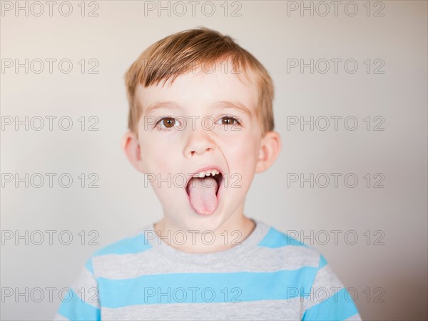 Studio Shot, Portrait of boy sticking out his tounge. Photo : Jessica Peterson