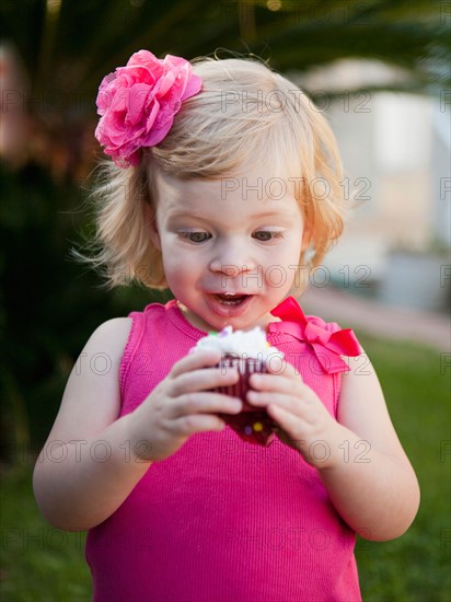 Girl with blong hair looking at cupcake. Photo : Jessica Peterson
