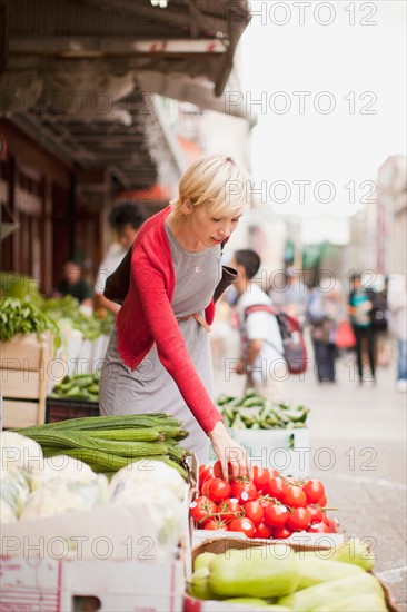 Woman pickig up fresh tomatoes at street market. Photo: Jessica Peterson