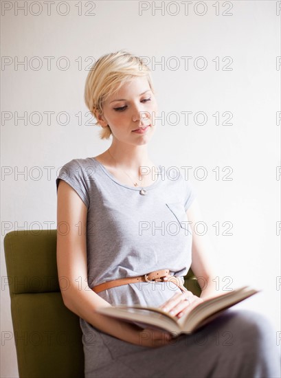 Studio shot, Portrait of sitting woman reading book. Photo: Jessica Peterson