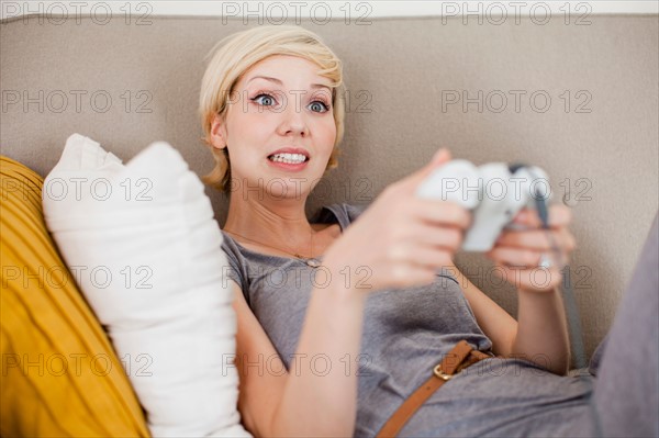 Woman laying on sofa and playing video game. Photo: Jessica Peterson