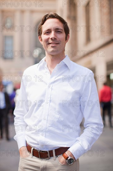 Portrait of man wearing white shirt and holding hands in his pockets. Photo : Jessica Peterson