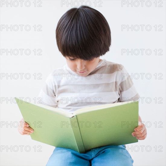 Studio Shot of young boy reading book. Photo: Jessica Peterson