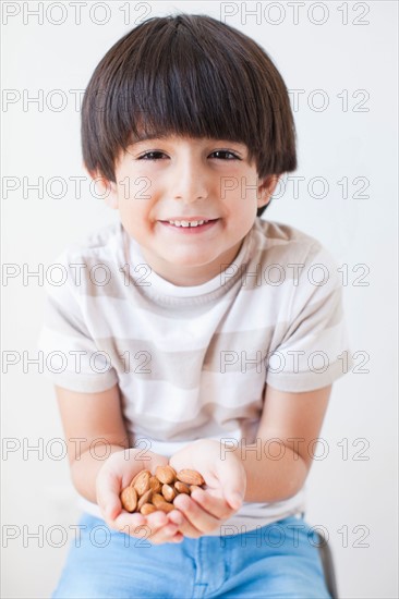 Studio Shot of young boy with almonds. Photo : Jessica Peterson