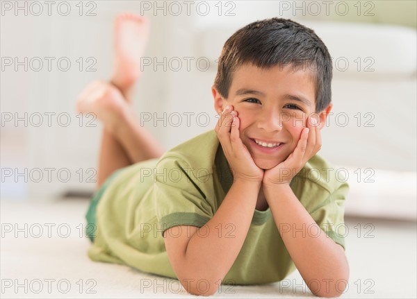 Portrait of boy (6-7) lying on carpet.