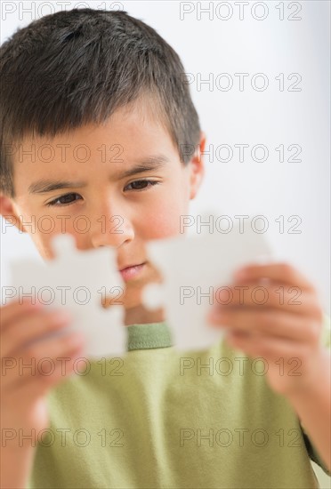 Boy (6-7) holding jigsaw pieces.