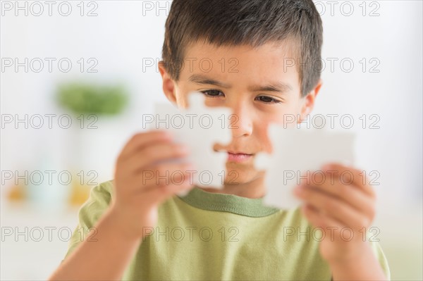 Boy (6-7) holding jigsaw pieces.