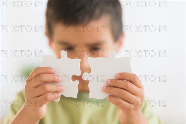 Boy (6-7) holding jigsaw pieces.