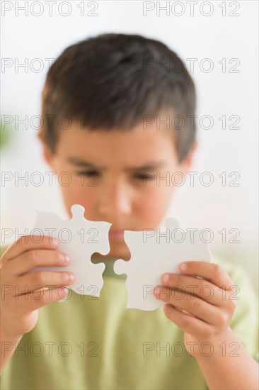 Boy (6-7) holding jigsaw pieces.