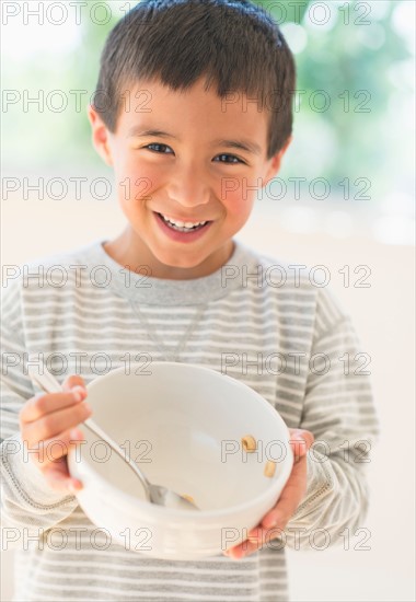 Boy (6-7) holding breakfast bowl.