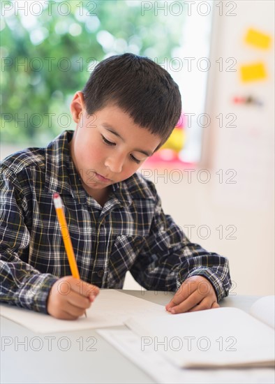 Boy (6-7) writing at school.