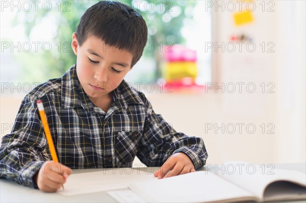 Boy (6-7) writing at school.