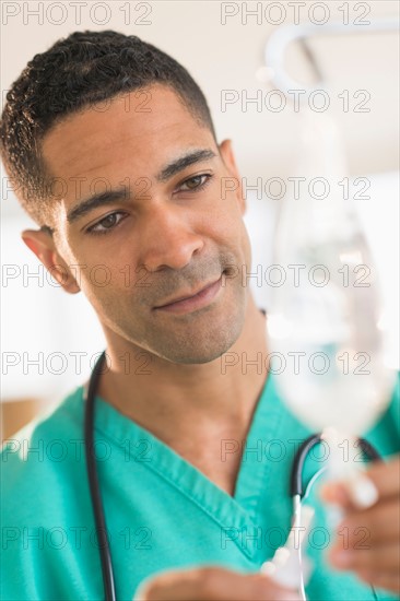 Male surgeon attaching iv drip on hospital.