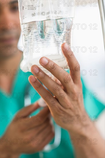 Male surgeon attaching iv drip on hospital.