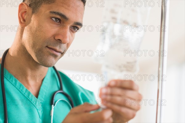 Male surgeon attaching iv drip on hospital.