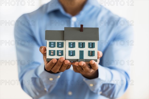 Man's hands holding model home.