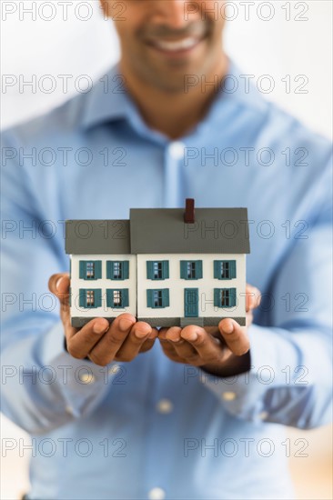 Man's hands holding model home.