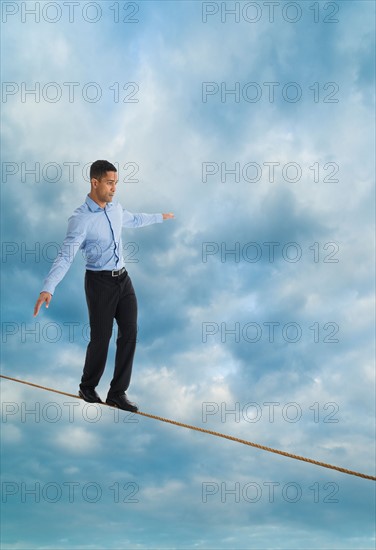 Man balancing on tightrope, studio shot.