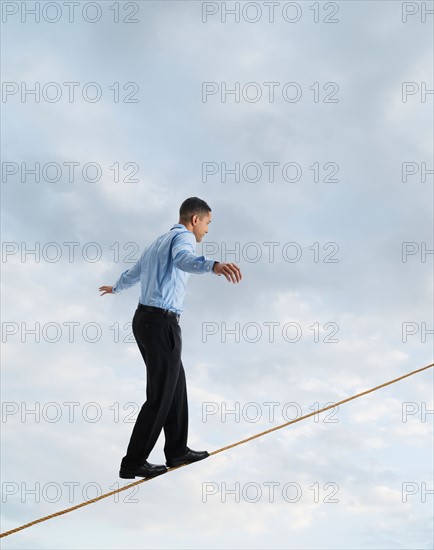 Man balancing on tightrope, studio shot.