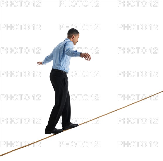 Man balancing on tightrope, studio shot.