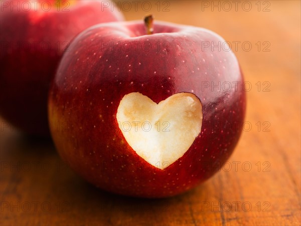 Close up of apple with missing bite in heart shape, studio shot.