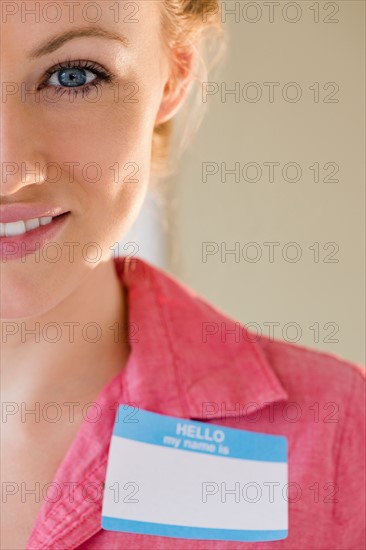 Portrait of smiling young woman with blank name tag