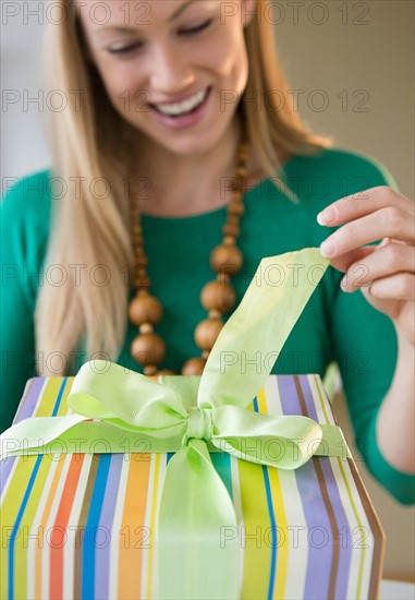 Smiling young woman opening birthday present