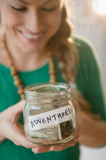 Young woman holding jar with money