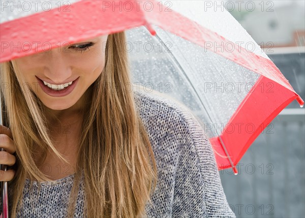 Smiling young woman with umbrella in rain