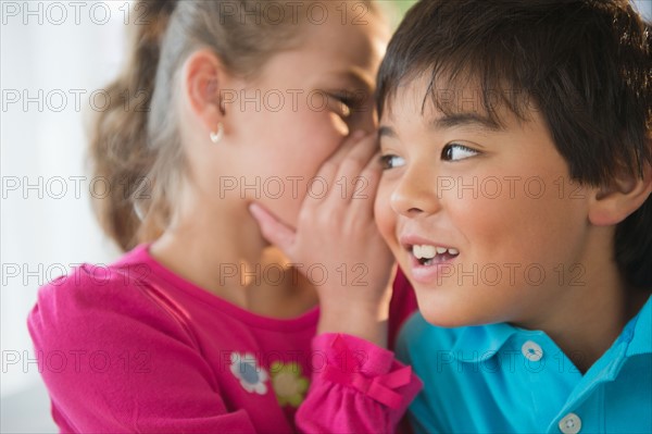 Girl (8-9) whispering into boy's (8-9) ear